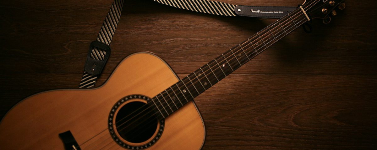 brown acoustic guitar on brown wooden floor