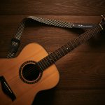 brown acoustic guitar on brown wooden floor