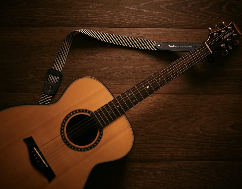 brown acoustic guitar on brown wooden floor