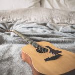 brown acoustic guitar on gray blanket